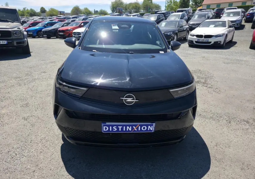 Vue avant d'un Opel Mokka noir avec calandre Vizor noire et logo Opel argenté, en extérieur sur parking.