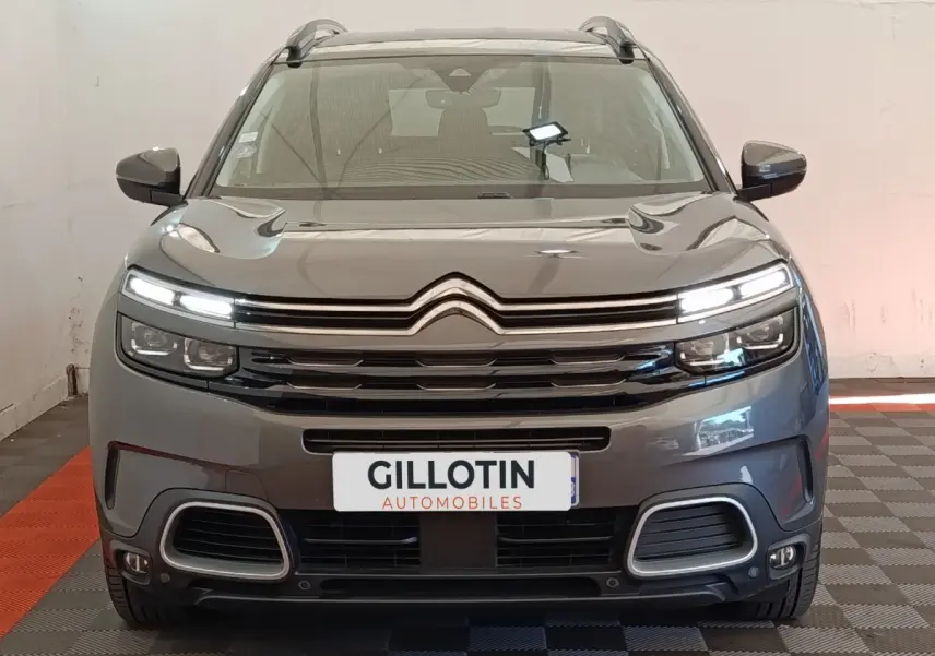 Vue frontale d'un Citroën C5 Aircross Hybrid gris foncé avec feux LED allumés et calandre distinctive.