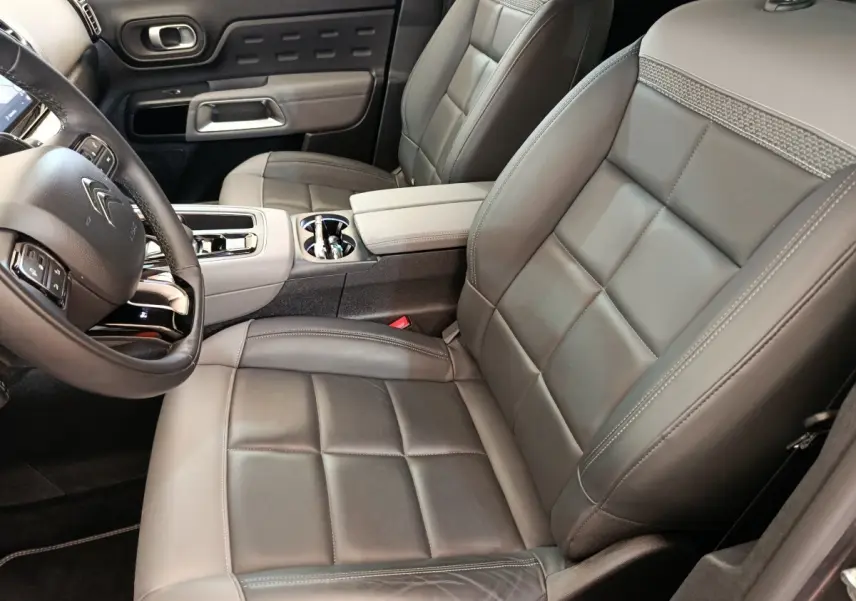 Vue intérieure côté conducteur du Citroën C5 Aircross Hybrid 225 avec sièges cuir gris et console centrale élégante.