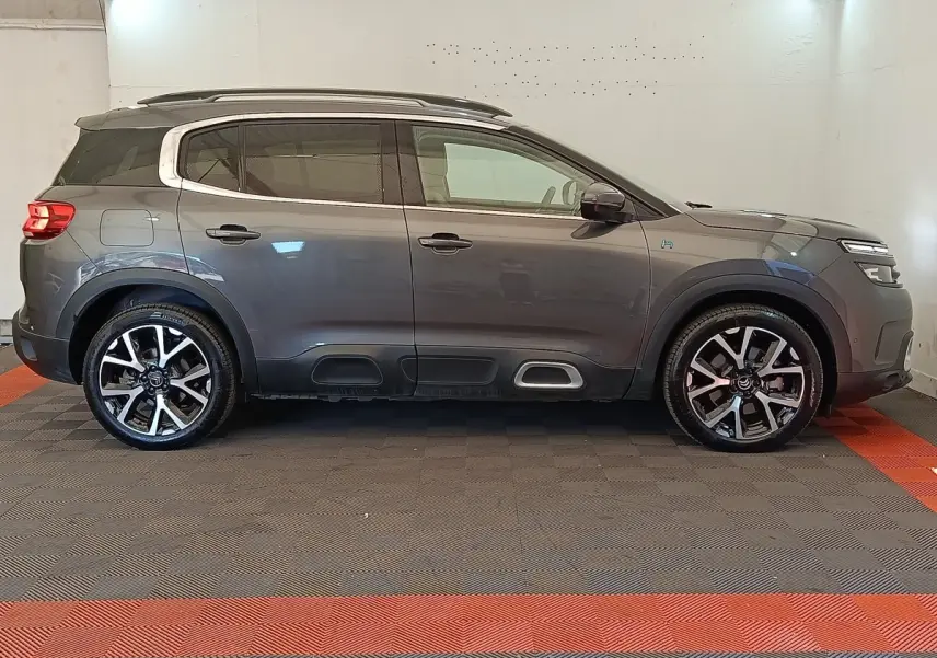 Profil droit du Citroën C5 Aircross Hybrid gris foncé avec jantes alliage et barres de toit chromées.