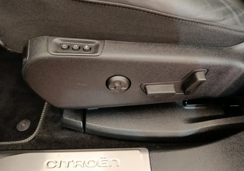 Détail des commandes de réglage du siège côté conducteur d’un Citroën C5 Aircross Hybrid 225 ë-EAT8 Shine Pack gris foncé.