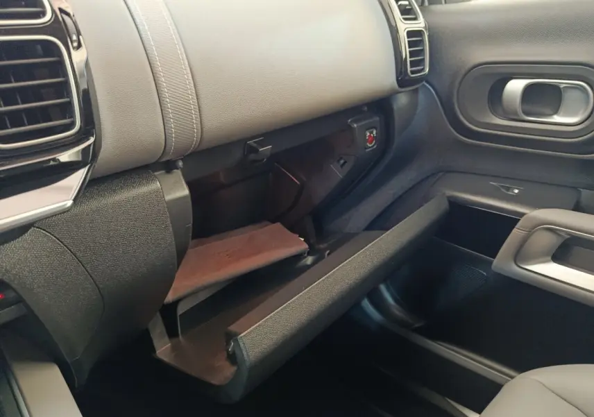 Intérieur côté passager du Citroën C5 Aircross Hybrid 225, boîte à gants ouverte avec finition cuir gris et plastique noir.