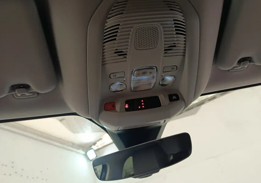 Vue intérieure du plafonnier gris clair avec commandes d’éclairage et rétroviseur intérieur d’un Citroën C5 Aircross Hybrid 225 Shine Pack.