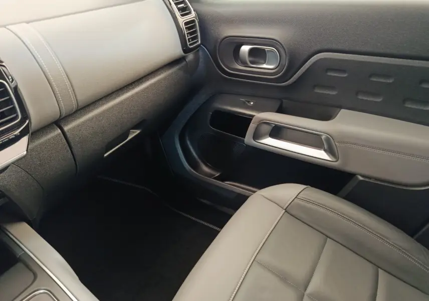 Intérieur gris clair du passager avant du Citroën C5 Aircross Hybrid, avec tableau de bord et porte au design moderne.