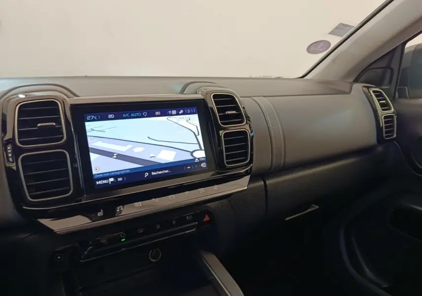 Vue intérieure côté passager du tableau de bord gris foncé du Citroën C5 Aircross Hybrid avec écran tactile de navigation allumé.