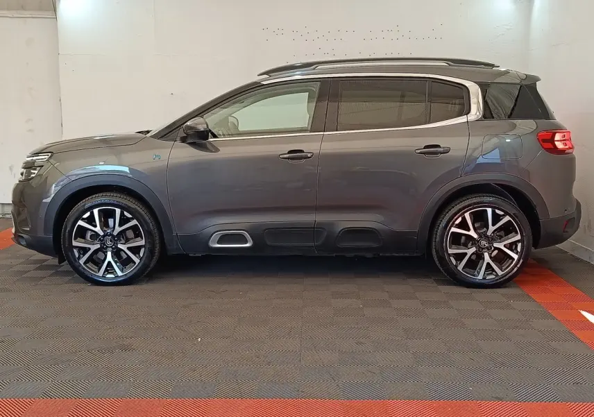 Profil droit d'un Citroën C5 Aircross Hybrid gris foncé avec jantes alliage et barres de toit chromées.