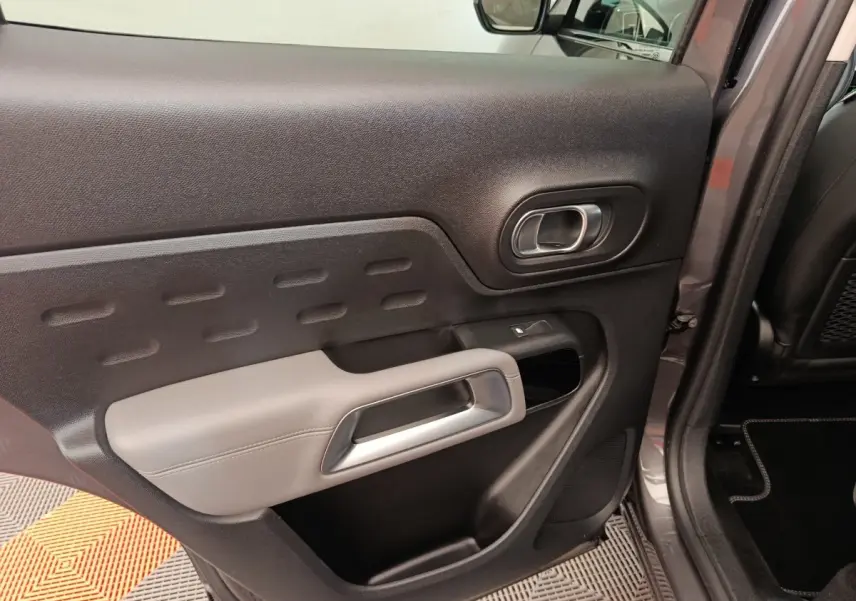 Vue rapprochée de la porte arrière droite gris foncé du Citroën C5 Aircross Hybrid avec accoudoir clair et poignée intégrée.