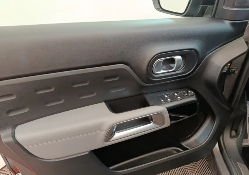 Intérieur côté conducteur de Citroën C5 Aircross Hybrid 225 ë-EAT8 Shine Pack, porte noire avec accoudoir gris clair et commandes électriques.