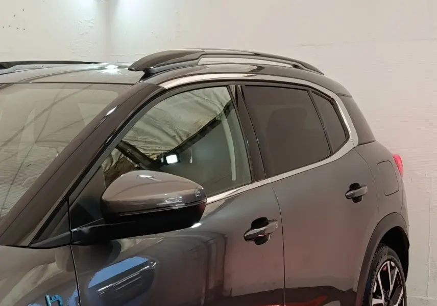 Vue de profil côté gauche d'un Citroën C5 Aircross Hybrid gris foncé avec barres de toit chromées et vitres teintées.