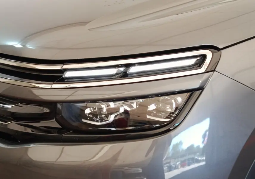 Gros plan sur le phare avant droit du Citroën C5 Aircross Hybrid gris foncé avec éclairage LED allumé.