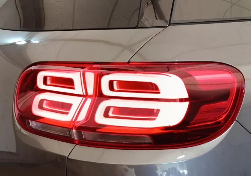 Gros plan sur le feu arrière droit rouge et blanc d’un Citroën C5 Aircross Hybrid gris foncé, vue latérale.