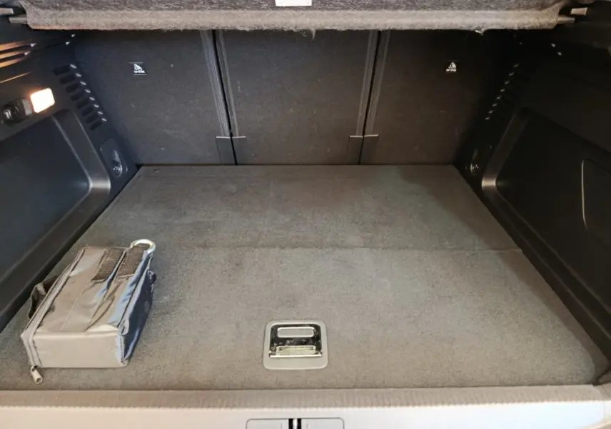 Coffre spacieux vu de face, intérieur gris foncé avec rangement noir et éclairage latéral allumé.