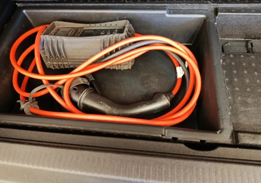 Câble de recharge orange rangé dans le compartiment de coffre du Citroën C5 Aircross Hybrid gris foncé.