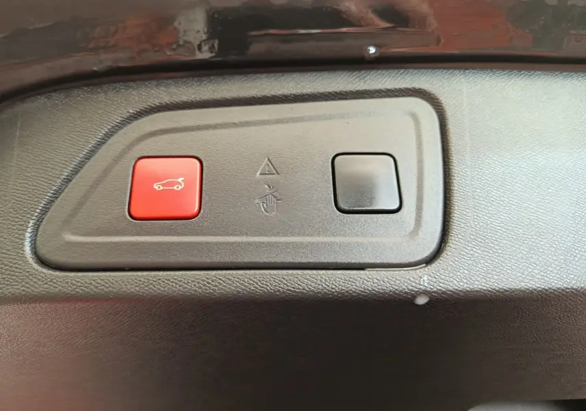 Gros plan sur les boutons d'ouverture du coffre, intérieur noir du Citroën C5 Aircross Hybrid 225 ë-EAT8 Shine Pack.