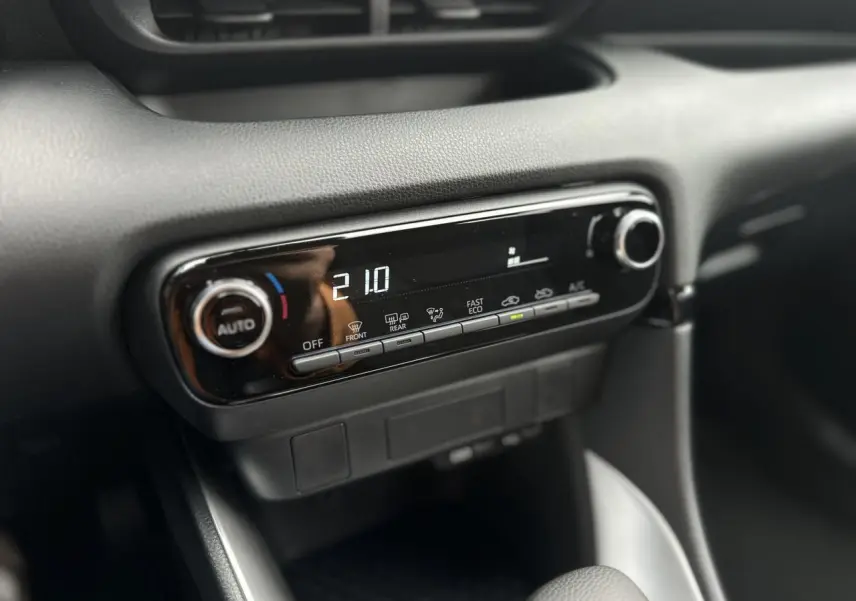 Gros plan sur la console centrale noire de la Toyota Yaris hybride 2025, affichant la climatisation automatique à 21°C.