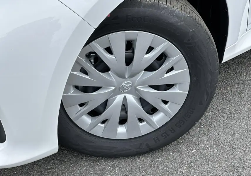 Gros plan sur la roue avant gauche de la Toyota Yaris Hybride blanche avec enjoliveur gris et pneu EcoContact 6.