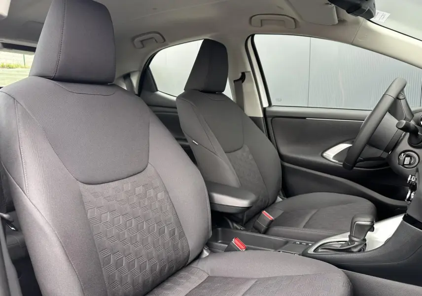 Intérieur de la Toyota Yaris Hybride 2025 vu côté droit, sièges tissu noir avec accoudoir central et boîte auto.