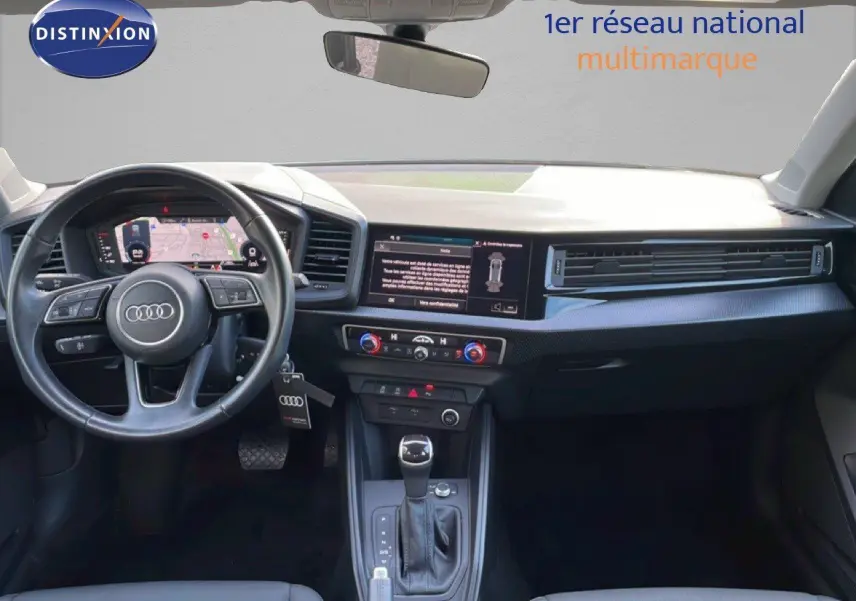 Intérieur de l'Audi A1 Sportback 2023 en blanc glacier, vue du tableau de bord avec volant et écran central tactile.