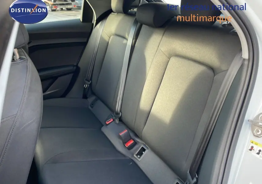 Vue intérieure sur la banquette arrière grise d'une Audi A1 Sportback blanche, avec ceintures de sécurité visibles.