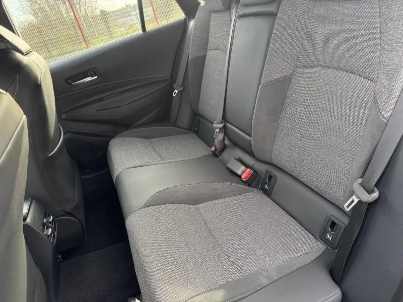 Vue intérieure côté droit de la banquette arrière grise et noire de la Toyota Corolla 2025 hybride avec ceintures et fixations Isofix visibles.