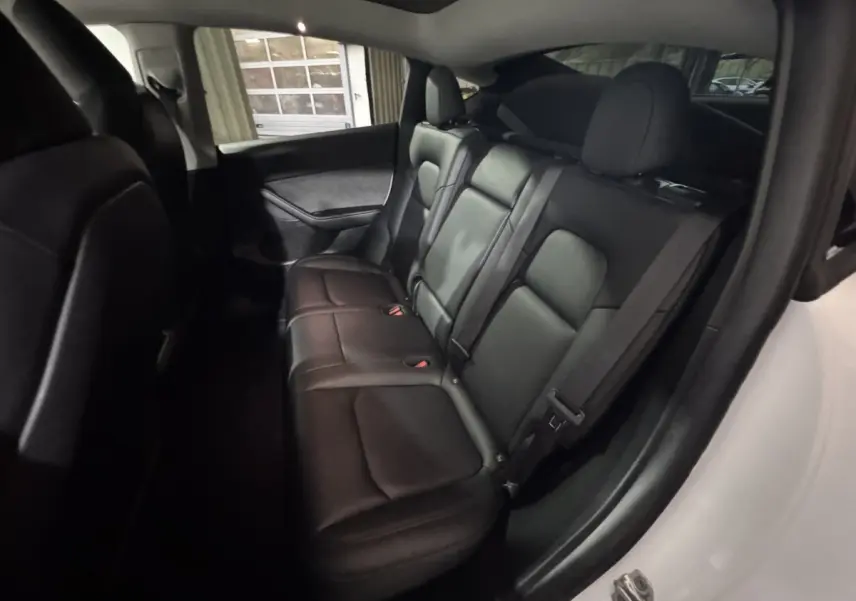 Vue intérieure côté droit des sièges arrière en cuir noir du Tesla Model Y blanc, version Grand Autonomie Dual Motor AWD.