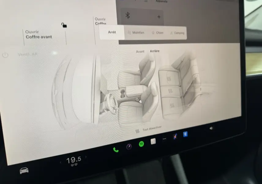 Écran tactile central affichant la configuration des sièges chauffants dans une Tesla Model Y blanche, vue intérieure.