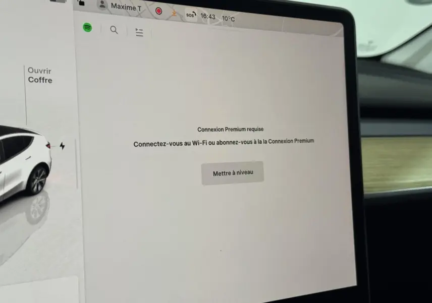 Écran tactile central de 15 pouces dans l’habitacle d’un Tesla Model Y blanc, vue rapprochée côté passager.