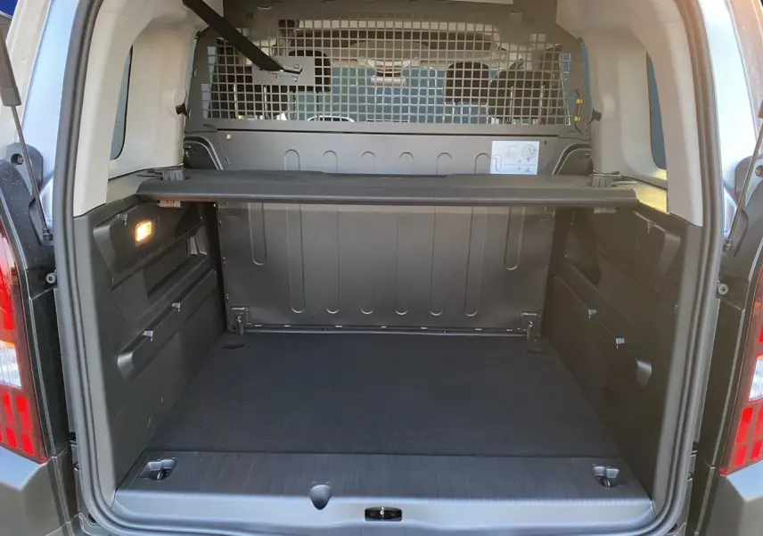 Coffre ouvert du Peugeot Rifter gris acier, vue arrière montrant la cloison métallique et le cache-bagages.