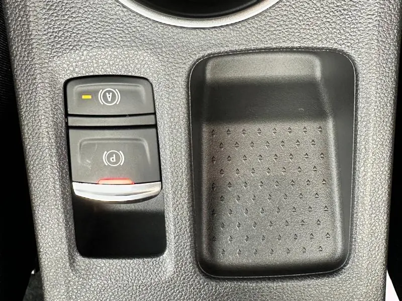 Gros plan sur la console centrale du Renault Captur 2025, montrant les boutons du frein à main électronique et du mode auto hold.