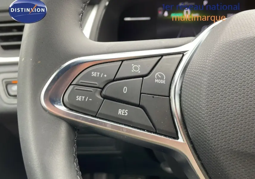 Gros plan sur les commandes de régulateur de vitesse au volant d’une Renault Symbioz gris Rafale Métal, intérieur noir.