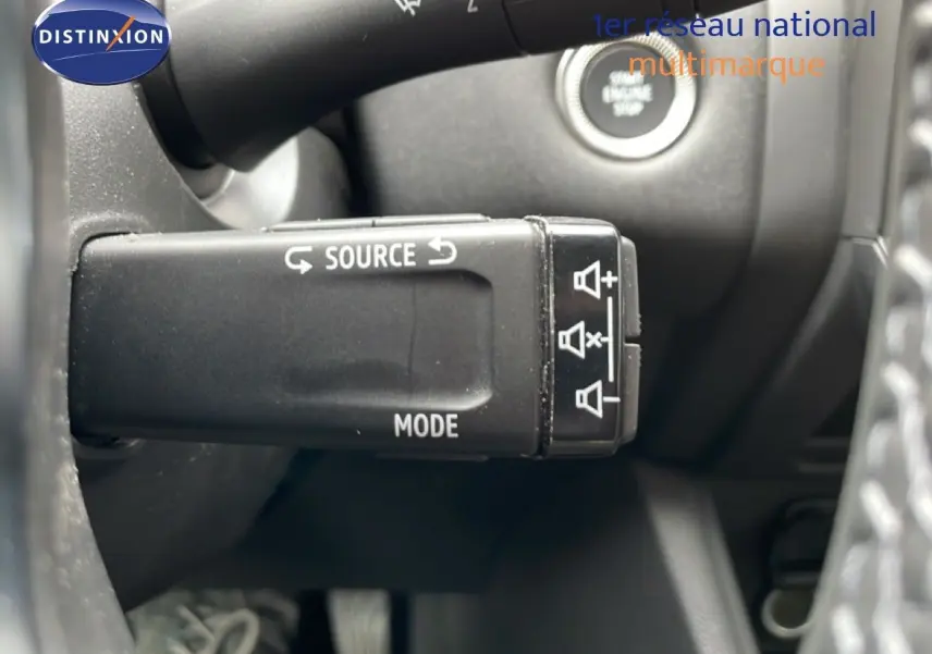 Gros plan sur la commande multimédia au volant du Renault Symbioz gris Rafale métal, avec bouton start visible en arrière-plan.