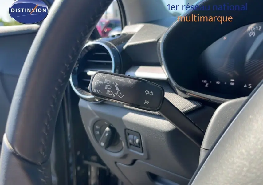 Vue intérieure rapprochée du volant et du commodo gauche d’une Skoda Fabia noire, mettant en valeur les commandes de régulateur de vitesse.