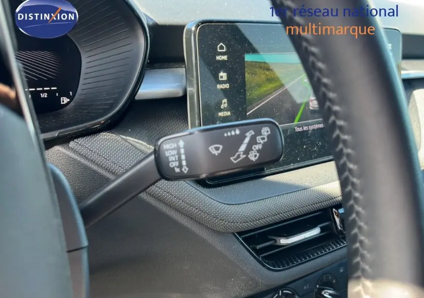 Intérieur de la Skoda Fabia 2025 en tissu gris noir, vue sur le volant et la commande d’essuie-glace avec écran tactile central.
