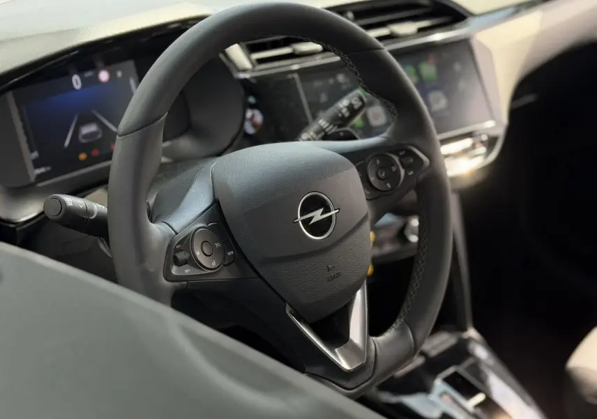 Vue intérieure centrée sur le volant multifonction noir de l’Opel Corsa 2025 avec écran tactile en arrière-plan flou.