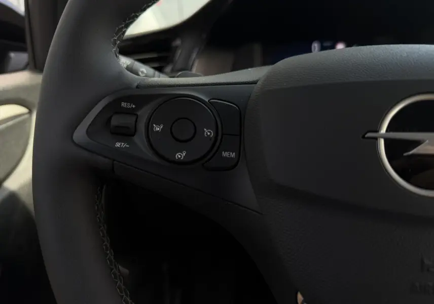 Gros plan sur les commandes de régulateur de vitesse à gauche du volant noir de l’Opel Corsa 2025.