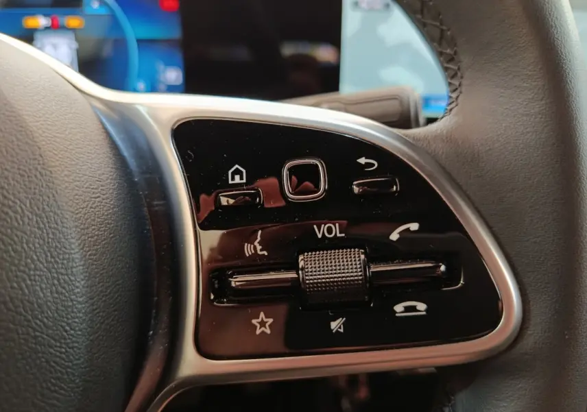 Gros plan sur les commandes multifonctions en cuir du volant côté gauche d’une Mercedes Classe A noire 2022.