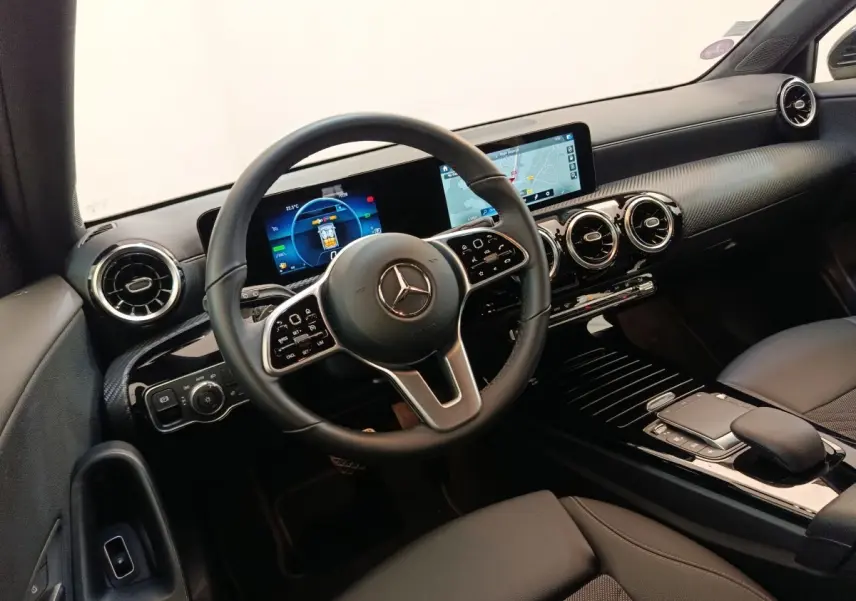 Vue intérieure du poste de conduite de la Mercedes Classe A noire, avec volant cuir multifonctions et écran tactile de navigation.