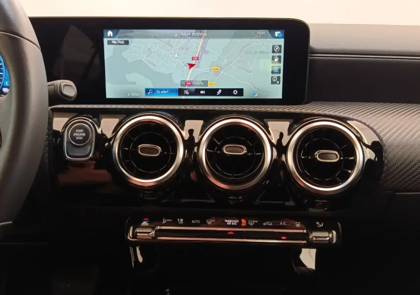Vue rapprochée du tableau de bord noir de la Mercedes Classe A 250 e avec écran tactile de navigation et aérateurs ronds chromés.