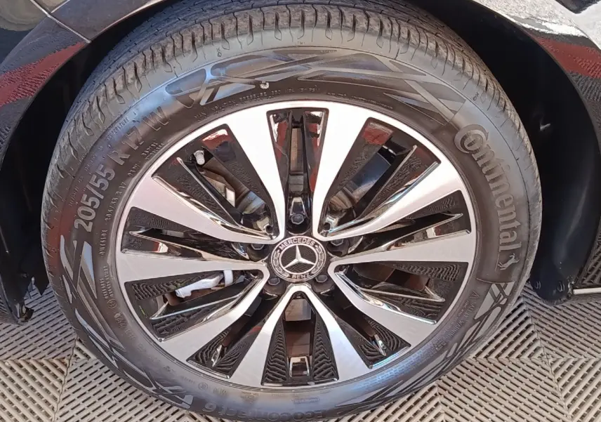 Gros plan sur la roue avant droite d’une Mercedes Classe A noire, mettant en valeur la jante alliage bicolore et le logo central.