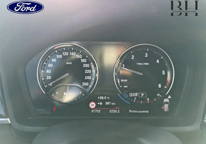 Tableau de bord BMW X1 sDrive18dA 2018 avec compte-tours, compteur vitesse, affichage digital et alertes visibles.