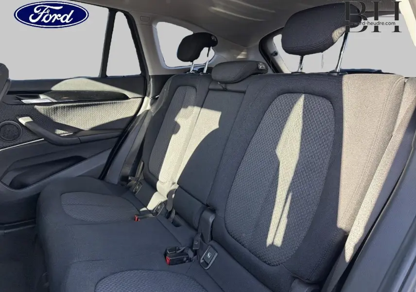 Vue intérieure arrière montrant la banquette tissu noire et les appuie-têtes d'un BMW X1 sDrive18dA 2018.