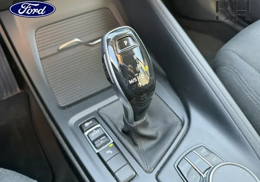 Le levier de vitesses automatique noir vu en gros plan dans l'habitacle d'une voiture, entouré de boutons de contrôle.