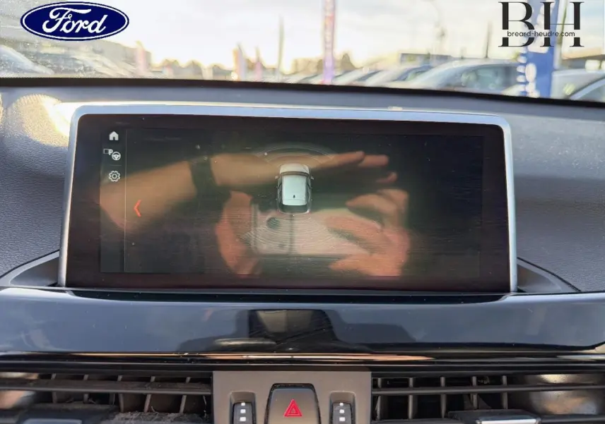 Écran central du tableau de bord d'une BMW X1 2018, vue frontale intérieure avec affichage de caméra de recul.