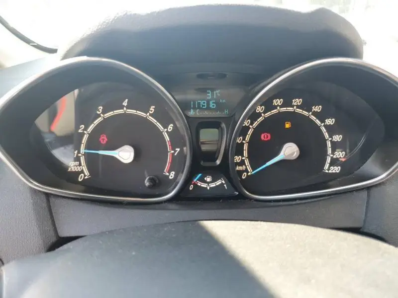 Tableau de bord de Ford Fiesta noir 2015, vue frontale sur compte-tours et compteur de vitesse avec voyants allumés.