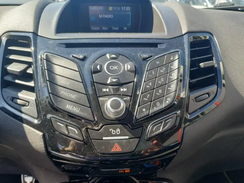 Tableau de bord central noir brillant de la Ford Fiesta 2015 avec commandes audio et écran multifonction.