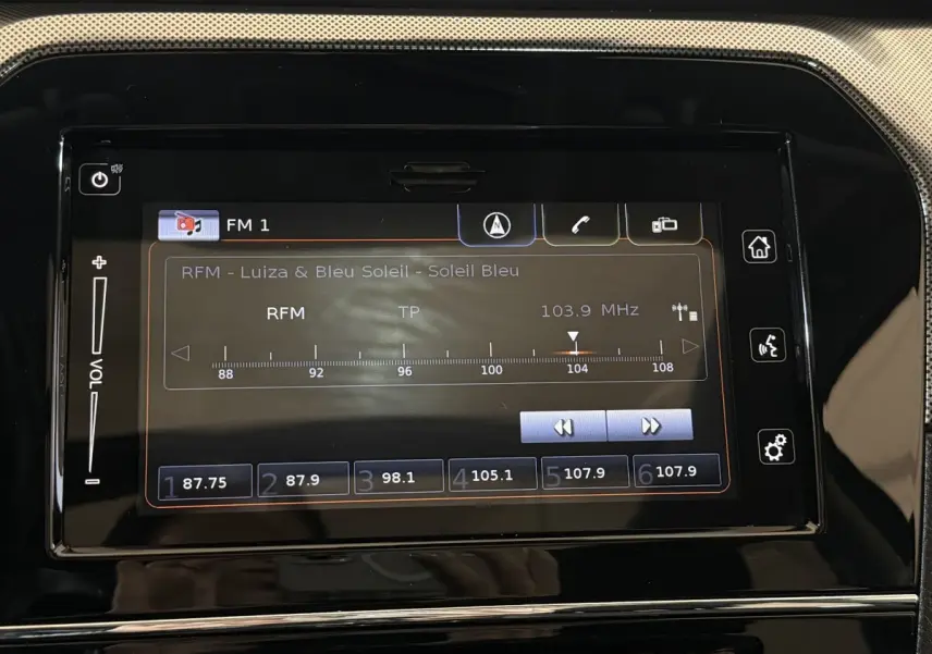 Écran tactile central du tableau de bord du Suzuki Vitara noir, affichant la radio FM sur 103,9 MHz.