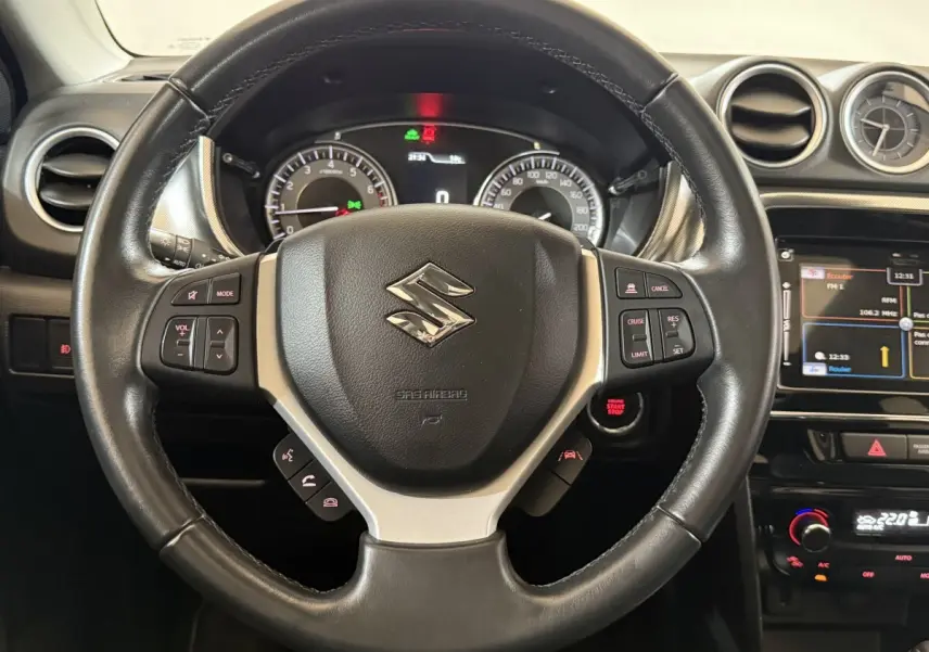 Vue rapprochée du volant cuir et alu noir du Suzuki Vitara 2022 avec tableau de bord et écran tactile visible.