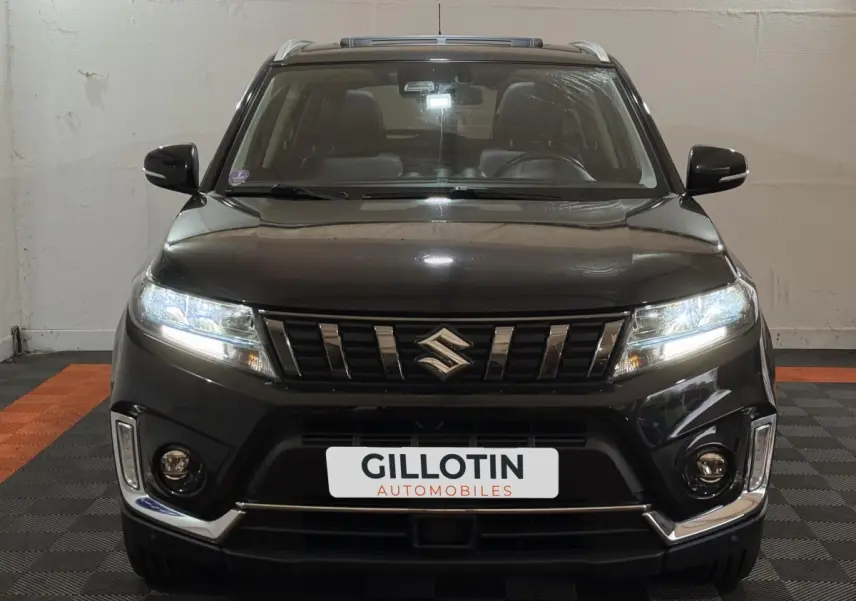 Vue frontale d'un Suzuki Vitara noir 2022 avec phares LED allumés et détails chromés sur le pare-chocs.
