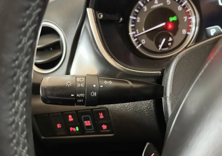 Gros plan sur la manette des phares et clignotants du Suzuki Vitara 1.5 Dualjet hybrid noir, tableau de bord en arrière-plan.