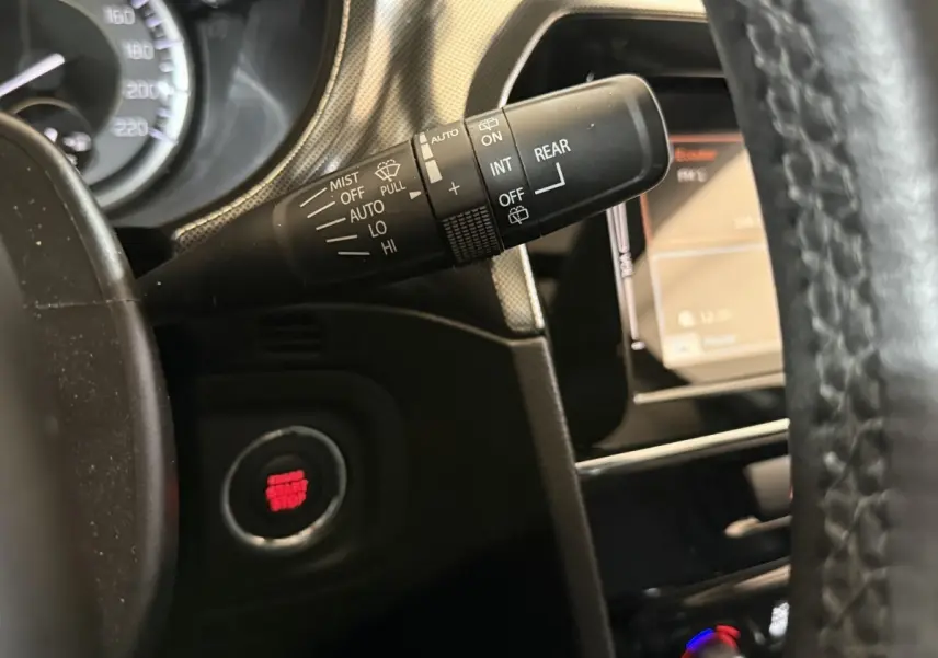 Gros plan sur la commande d’essuie-glace et bouton démarrage rouge du tableau de bord noir du Suzuki Vitara 1.5 Hybrid.